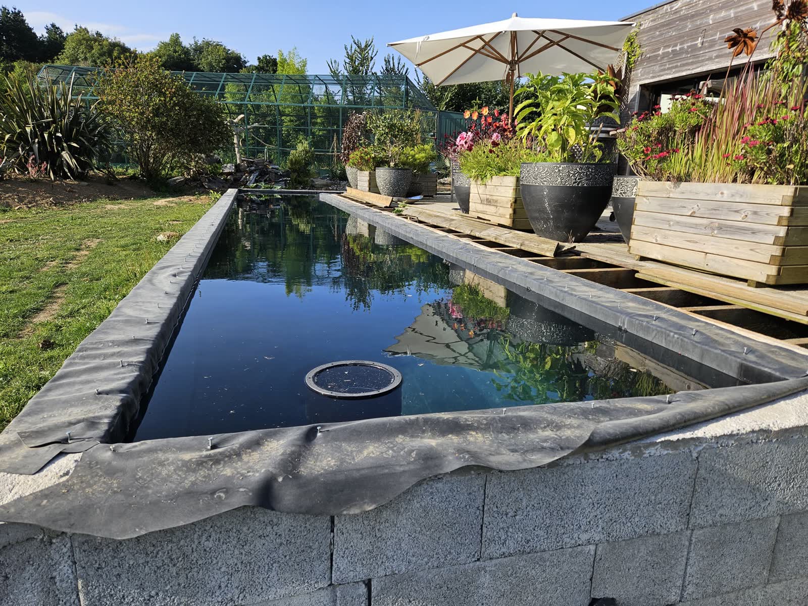 Bassin en eau au soir, terrasse bois et maison en arrière-plan — Plestin-les-Grèves